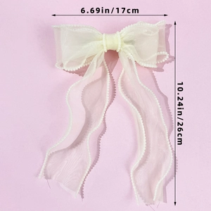 Detail of off-white chiffon bow hair clip with faux pearl trim and long streamers