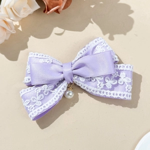 Detail of lavender satin bow hair clip with white floral lace and dangling pearl charm
