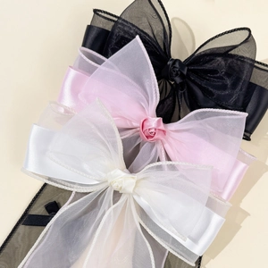 Close-up of three layered tulle bow hair clips with central fabric roses in pink, black, and cream