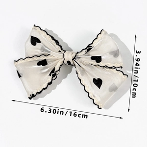 Detail showing white satin bow hair clip with black hearts and 16cm width measurement