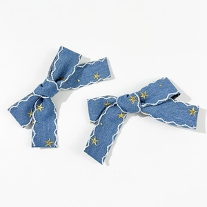 Détail de la broderie étoile et coutures ondulées sur une paire de barrettes denim