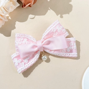 Close-up detail of pink lace bow hair clip with a delicate pearl pendant decoration