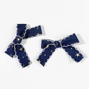 Vue détaillée de barrettes en denim avec étoiles dorées et bords brodés blancs