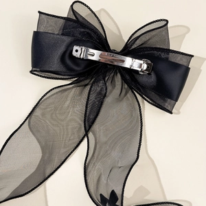 Detail of black mesh bow hair clip featuring a silver metal spring clip with Paris engraving