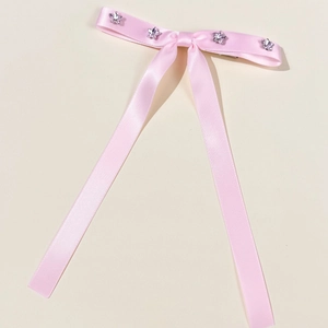 Dettaglio del fermaglio per capelli con fiocco in raso rosa e strass a stella