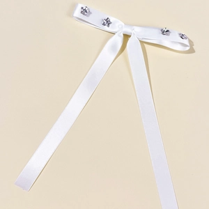 Dettaglio del fermaglio per capelli con fiocco in raso bianco e strass a stella