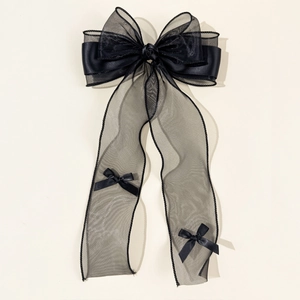 Detail of elegant black mesh bow hair clip with satin ribbons and floral center piece