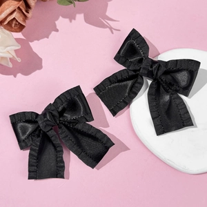 Paar elegante schwarze Satin-Haarschleifen mit Rüschenkanten auf rosa Hintergrund