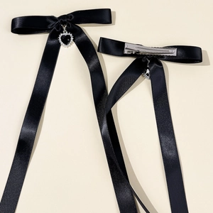 Détail recto verso des barrettes nœuds en satin noir avec pendentifs cœur en cristal