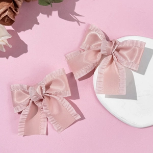 Rosa Satin-Haarspangen mit Rüschenkanten für Damen auf einem eleganten Steintablett