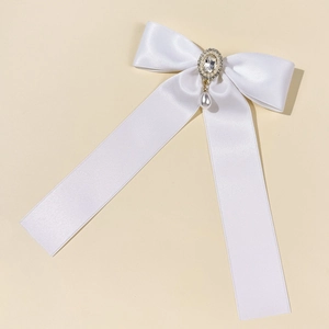 Detailed close-up of a white satin bow hairpin with pearl and rhinestone center