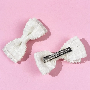 Dettaglio di fermagli per capelli con fiocco in pizzo bianco e clip a becco in metallo