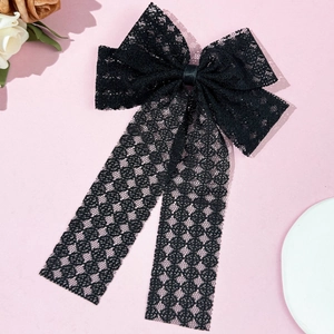 Détail d'un nœud à cheveux en dentelle noire avec broderie florale et longs rubans