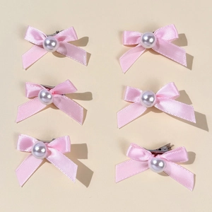 Détail de barrettes à nœuds roses avec perles blanches sur pinces en métal argenté