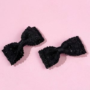 Dettaglio delle mollette in tweed nero con glitter argento e bordi a conchiglia