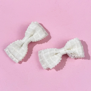 Dettaglio dei fermagli per capelli a fiocco in pizzo bianco con trama a rete fine