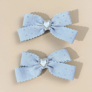 Détail de barrettes nœuds bleu clair avec bords festonnés et strass en forme de cœur