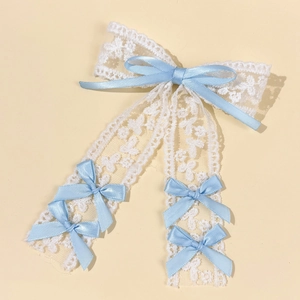 Close-up of white lace hair clip featuring elegant light blue satin ribbon bows
