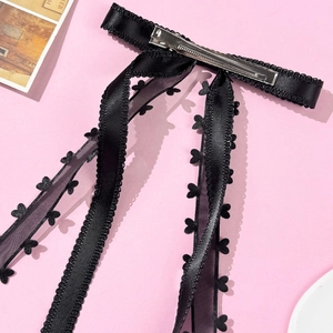 Dettaglio di fiocco nero per capelli con pizzo a cuore e clip in metallo