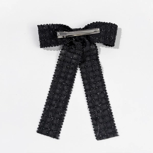 Close-up of black textured ribbon bow hair clip with silver alligator clip and wavy edges