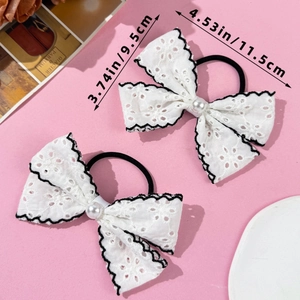 Detail of white lace bow hair ties with pearl center and black wavy embroidery edges