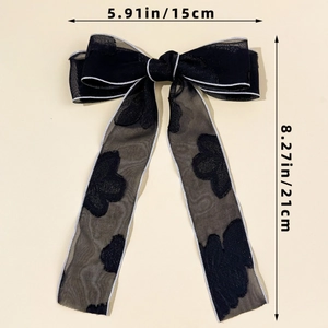 Dettaglio del fermaglio a fiocco in rete nera con ricami floreali e misure 15x21cm