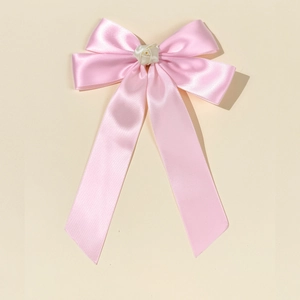 Dettaglio ravvicinato di un fiocco di raso rosa con una delicata rosa di stoffa bianco panna