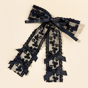 Detail view of large black lace hair clip with long ribbons and ribbon decorations