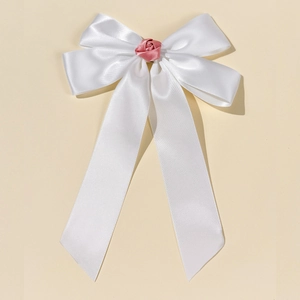 Dettaglio del fermaglio a fiocco bianco con rosa rosa su uno sfondo beige neutro