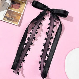 Dettaglio del fermaglio per capelli in raso nero con nastri in pizzo a forma di cuore