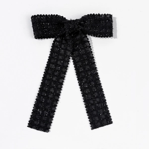 Detail of elegant black ribbon bow clip with silver metallic thread and scalloped edges