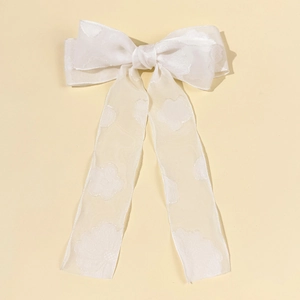 Dettaglio del fiocco per capelli bianco in organza floreale con ricamo jacquard