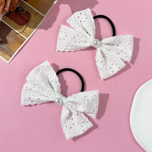Detail of white lace bow hair ties with pearl center and floral embroidery patterns