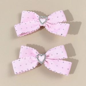 Lot de barrettes noeuds roses avec strass en forme de cœur sur fond beige chaleureux