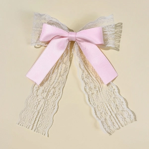 Detailed close-up of a sweet pink satin ribbon hair clip with white floral lace streamers