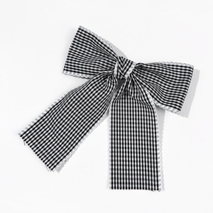Détail d'un nœud à cheveux à carreaux vichy noir et blanc avec bordure en dentelle
