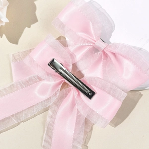 Détail de barrettes à nœuds en organza rose avec pince crocodile en métal argenté