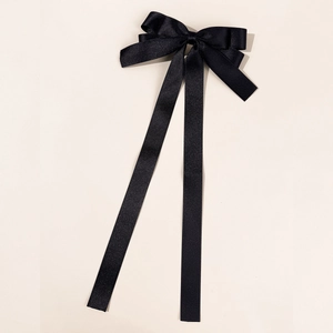 Detail of elegant black satin ribbon bow hair clip with long flowing streamers