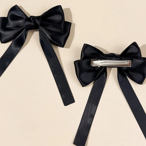 Detail von schwarzen Satin-Haarschleifen mit langen Bändern und silbernen Metallclips