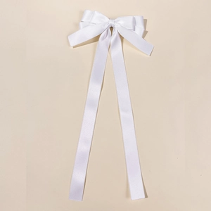 Detailed close-up of white satin bow hair clip with elegant long hanging ribbons