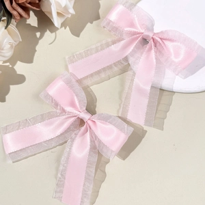 Détails de pinces à cheveux avec nœuds en résille et satin rose sur fond beige