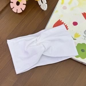 Detail of white knit baby headband with central twist knot on a domestic background
