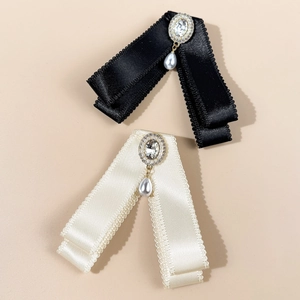 Close-up of elegant ribbon bow brooch with crystal rhinestone and drop pearl detail