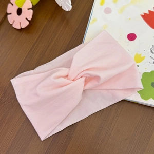 Close-up of soft pink twisted cotton headband for babies on a warm wooden background
