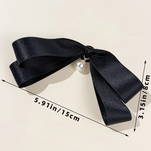 Detailed macro view of black satin bow with pearl pendant showing 15cm width dimension