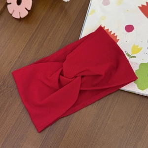 Close-up of red knotted elastic baby headband on a dark wooden textured background
