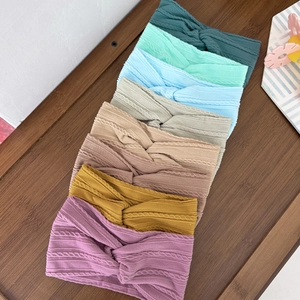Set of 8 colorful knitted cable knit baby headbands with crossover knots on wooden background