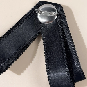 Detailed macro view of the black satin ribbon bow back with silver safety pin fastener