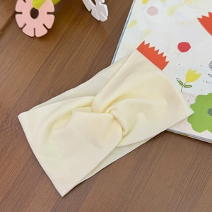 Detail of soft pale yellow twisted baby headband on a rustic wooden surface backdrop
