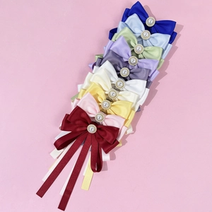 Close-up of colorful satin bow ties with faux pearls and long ribbon tassels